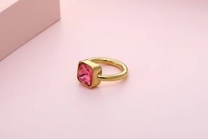 Detail of square pink zircon stone on wide polished gold plated stainless steel ring