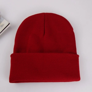 Detailed top view of a dark red ribbed knit beanie on a clean light gray background