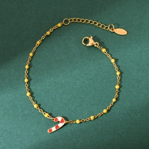 Detail of a gold stainless steel bracelet with a candy cane pendant on green background