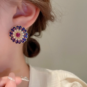 Detail of vintage flower stud earring with purple enamel and rose red stone on ear