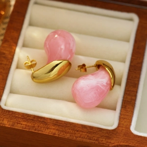 Detail of pink marble resin hoop earrings in a wooden jewelry box with 18k gold plating