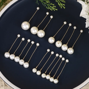 Macro detail of handmade bridal pearl hairpins with gold wires on a deep blue plate