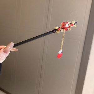 Detail of wooden hair stick featuring red flower petals and elegant beaded tassels