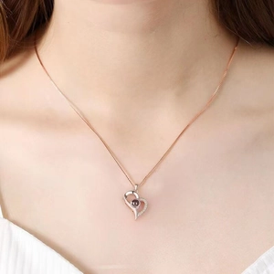 Close-up of rose gold heart pendant with zircon inlay worn by a female model