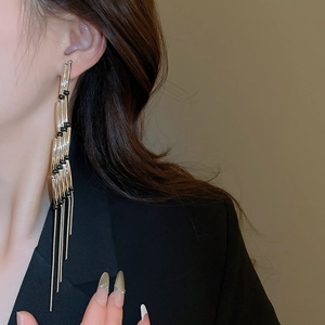 Close-up of cascading rectangular metal tassel earrings with black bead accents