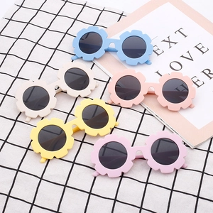 Kids flower shaped sunglasses in five colorful macaron shades on a plaid background