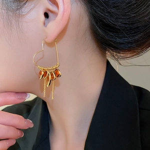 Macro side view of model wearing vintage 18K gold plated crystal heart tassel earrings
