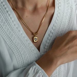 Vintage gold snake chain necklace featuring a square pendant with heart shaped gemstone