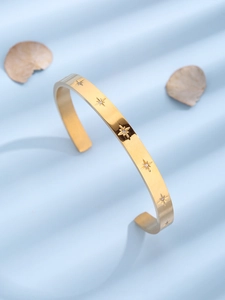 Detail of C-shaped stainless steel star bracelet with inlaid crystals on blue background