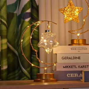Detail of warm LED moon and star lamp with copper metal frame and glass star pendant