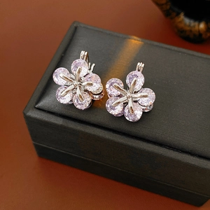 Détail de boucles d'oreilles fleurs avec zircons roses et base en argent sur un écrin
