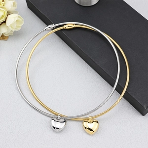 Polished gold and silver heart pendant necklaces with sleek snake chains on a gift box