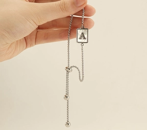Detail of silver stainless steel chain bracelet with a mother of pearl letter A pendant