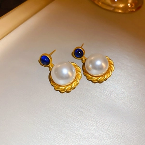 Detail of vintage French style pearl earrings with blue gemstone and gold twisted frame