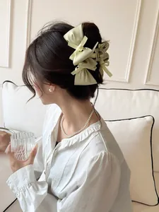 Detail of a large cream-colored bow hair claw clip worn on elegant hairstyle