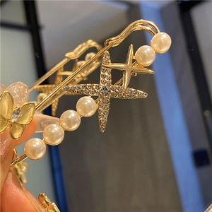 Detail of a gold safety pin brooch with sparkling stars, pearls, and a yellow butterfly