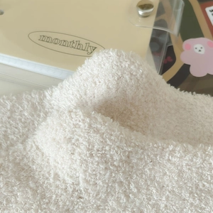 Macro detail of soft cream teddy fleece coral velvet fabric texture with cozy decor