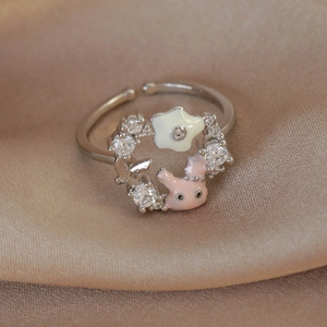 Macro shot of silver butterfly and pink rabbit heart ring with zircons on silk