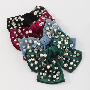 Dettaglio di fermagli per capelli in velluto con strass e perle in quattro colori