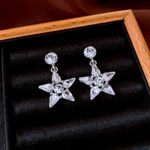 Detail of star-shaped earrings with crystals on black velvet in a wooden jewelry box