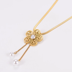 Macro shot of gold floral necklace with hollow clover pendant and pearl tassel detail