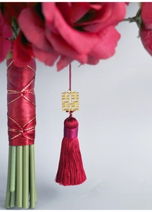 Detail of Chinese wedding bouquet handle with red silk tassel and golden Xi symbol charm