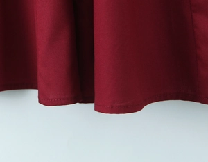 Gros plan sur l'ourlet de la robe rouge montrant les coutures et la texture du tissu