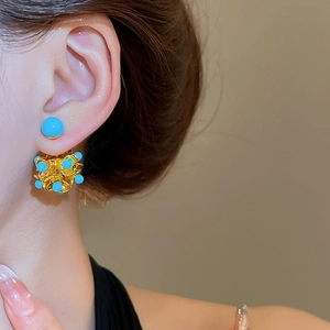 Detailed view of silver needle resin flower earrings worn on the earlobe with gold frame