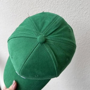 Detail of the stitched eyelets and textured cotton fabric on top of a dark green baseball cap