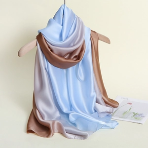 Detail eines seidigen Schals mit blau-silber-braunem Farbverlauf an einem Holzbügel hängend