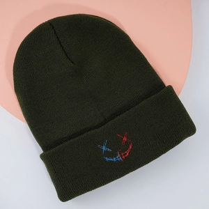 Détail du bonnet en maille vert foncé avec broderie bicolore rouge et bleue du visage