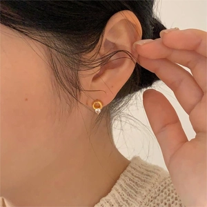 Close-up of golden circle stud earring with sparkling zircon on model ear