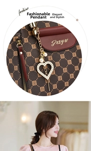 Detail of a brown monogram handbag featuring a gold heart charm and pearl accent