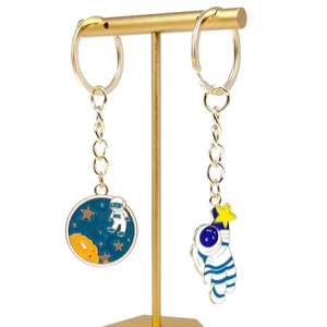 Astronaut keychain set with planet pendant and star charms on a gold display stand