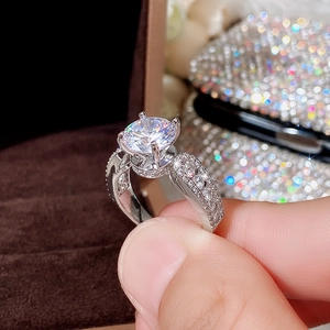 Macro view of classic four-prong engagement ring with round clear zircon and pave setting