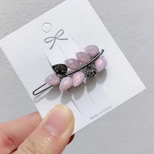 Handheld view of pink leaf flower hair clip with rhinestones and black metal frog buckle