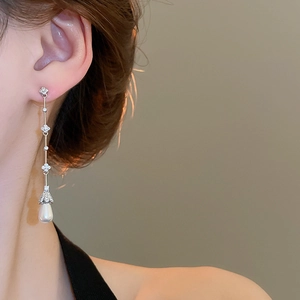 Detail of elegant gold drop earrings with zircon flowers and pearls on a model
