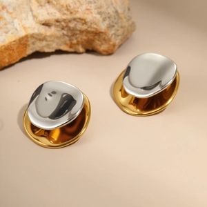 Detail of two-tone gold and silver stainless steel geometric earrings on a rock
