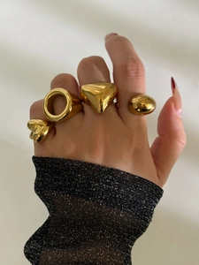 Detailed view of four chunky gold geometric rings with heart and triangle shapes