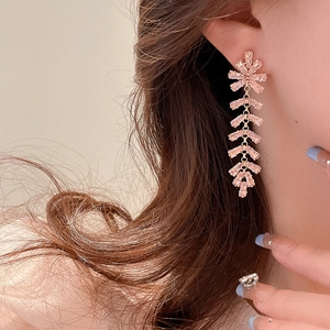 Detailed view of long pink crystal fringe earrings worn by a model in soft golden light
