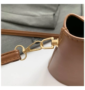 Close-up of golden hardware hook and strap connection on brown leather bucket bag