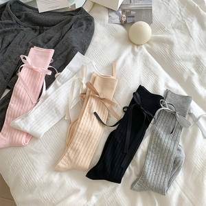 Detail view of five pairs of ribbed knit socks with satin bows in pink white and grey