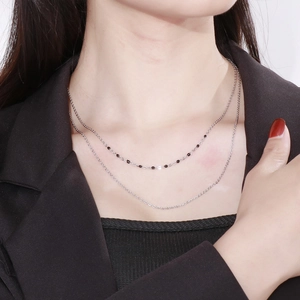 Double-layered silver stainless steel necklace with black beads on a model's neck