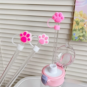 Detail of pink silicone cat paw straw cover on a cup with soft lighting background