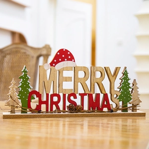 Wooden Merry Christmas tabletop sign with red tree and hat decorations on a rustic wood surface