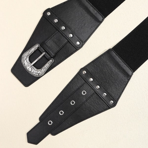 Detail of vintage carved silver buckle on a wide black elastic waist belt with rivets