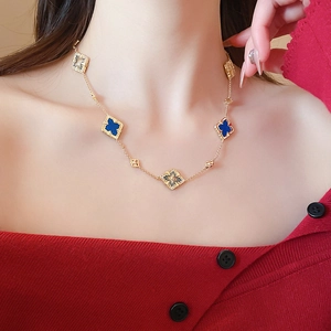 Close-up of gold plated four-leaf clover necklace with blue enamel and hollow pendants