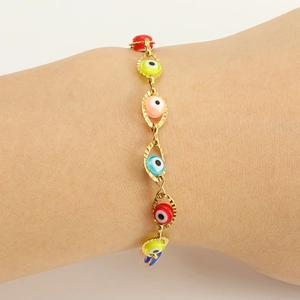Vue macro d'un bracelet en chaîne plaqué or 18K avec breloques Evil Eye colorées au poignet