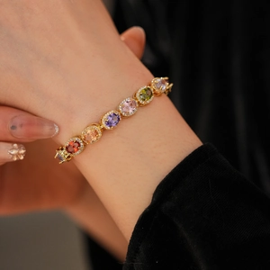 Close-up of a vintage gold bracelet with colorful oval-cut stones and zircon inlay