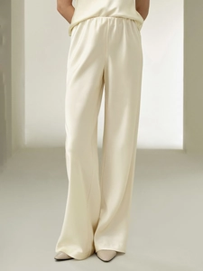 Detail of cream satin wide-leg trousers showing elastic waistband and silky texture